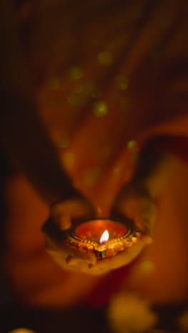 Vertical-Video-Close-Up-Of-Woman-Celebrating-Festival-Of-Diwali-Holding-Lit-Diya-Oil-Lamp-2